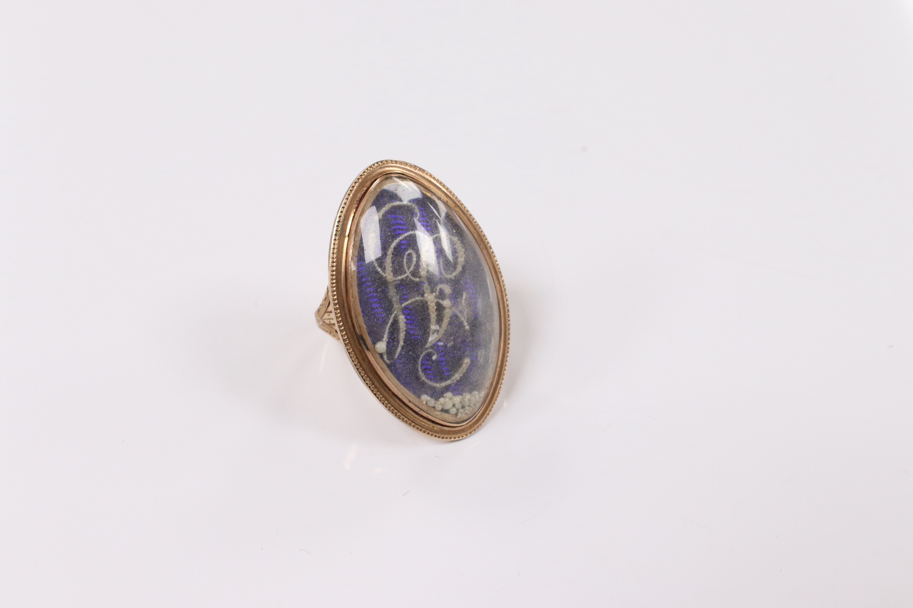 A George III yellow metal, enamel and simulated seed pearl set initialled oval mourning ring, with engraved inscription, 'Isaac Sparks ob. 17th Jan, 1788 ae. 60' size G/H, gross weight 7.6 grams. Condition - poor